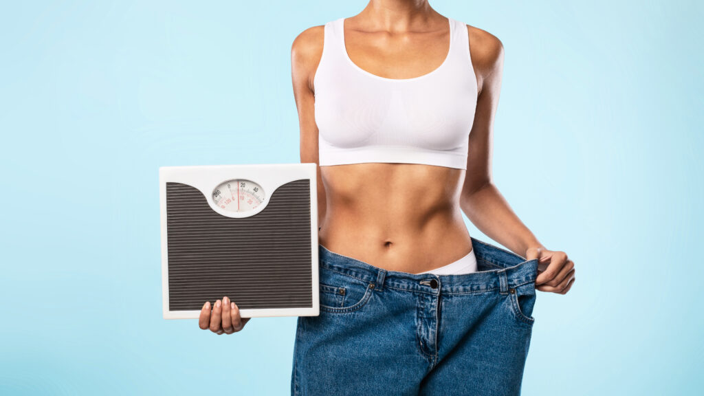 Woman Holding Scales Pulling Her Old Large Jeans thumbnail